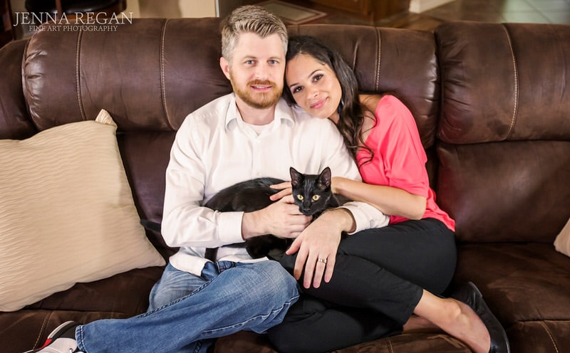 black cat on couch with parents in home photo shoot