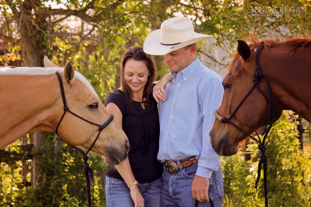 married couple standing with their horses on ranch