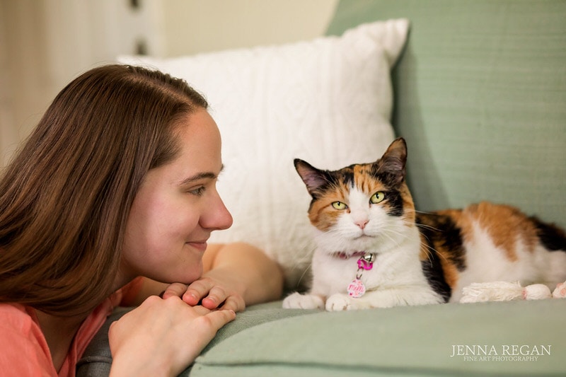 photo shoot of calico cat and mom on couch in home photo shoot with pet photographer
