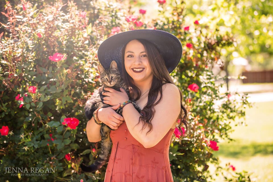 senior girl posing by roses with pet cat